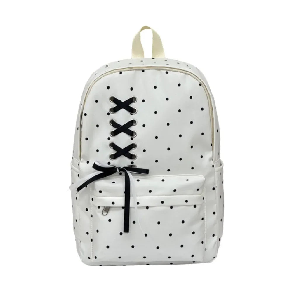 A white corduroy backpack with a bow print design and black crisscross straps.
