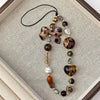 A leopard print bowknot phone lanyard featuring various heart-shaped beads and a black cord.
