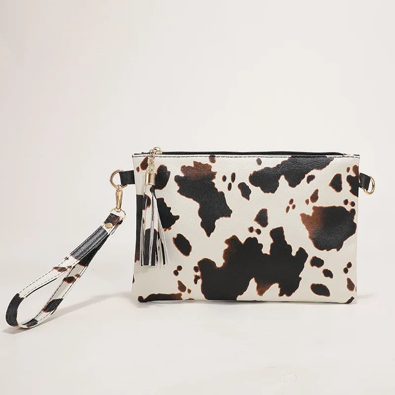 A white and black leopard print faux leather wrist bag with gold hardware.