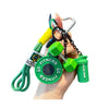 A hand holds a fitness keychain featuring a dumbbell and kettlebell charm with green and black chains.
