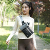 A woman wearing a beige long-sleeved top and brown pants holds a black waterproof invisible waist pack for runners and travel
