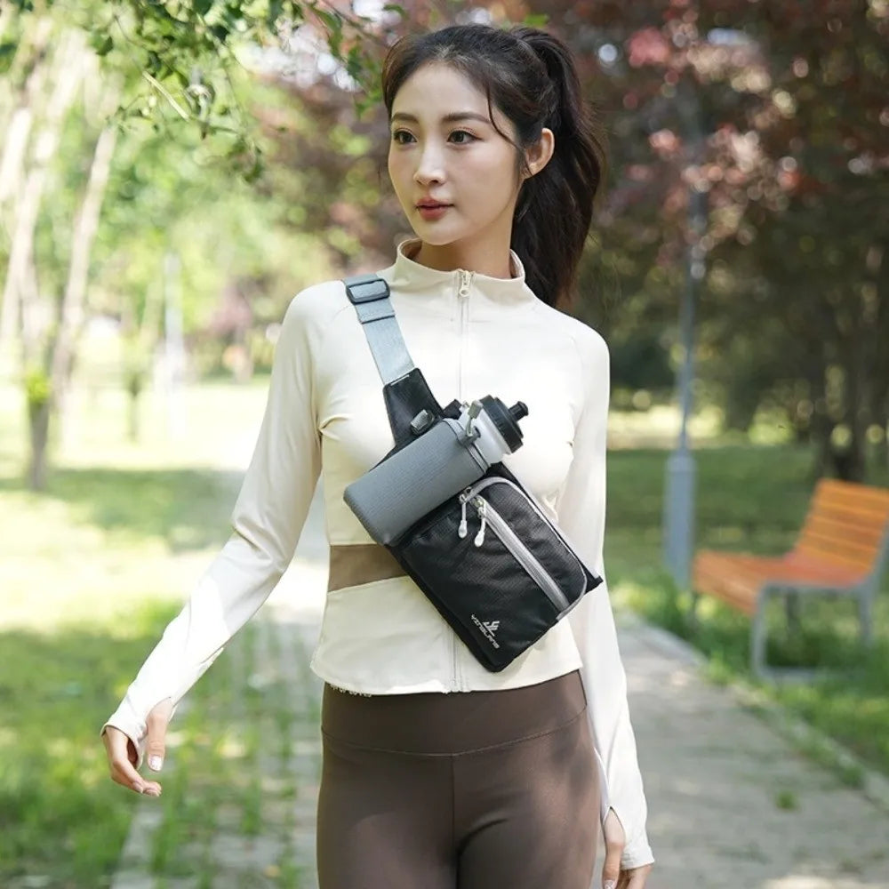 A woman wearing a beige long-sleeved top and brown pants holds a black waterproof invisible waist pack for runners and travel