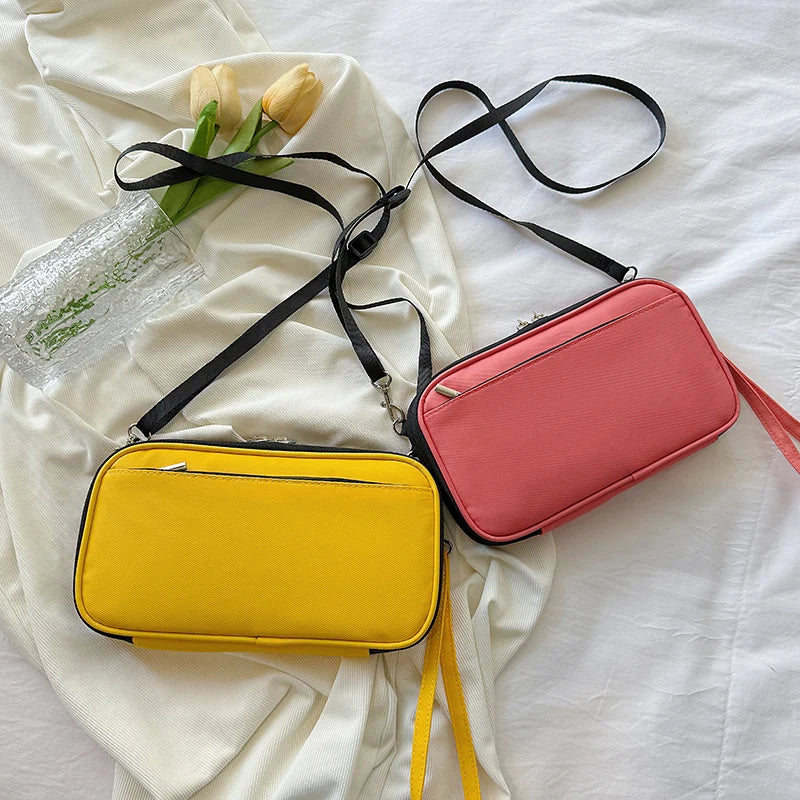 A pink and yellow multi-pocket waterproof travel document organizer with black straps lying on a white cloth.