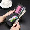 A hand holds a black zippered wallet with various credit cards and cash inside, next to a white cup and saucer.
