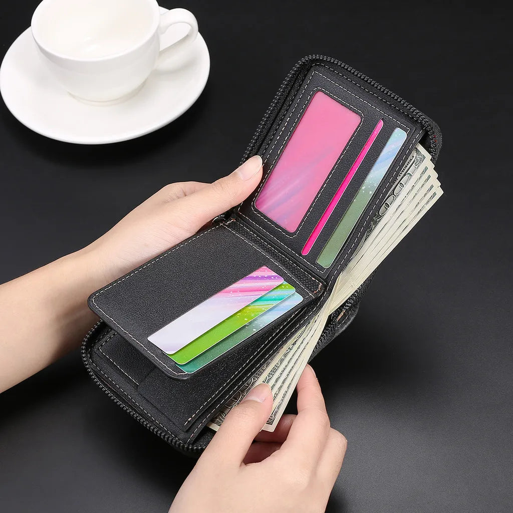 A hand holds a black zippered wallet with various credit cards and cash inside, next to a white cup and saucer.