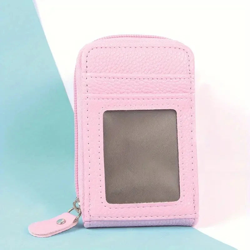 A pink leather card holder wallet with a clear slot and a silver clasp is shown against a light blue background.