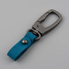 A close-up view of a genuine leather keyring keychain with a silver clasp and a teal fabric strap.
