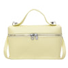A pale yellow minimalist pebbled leather box crossbody bag with a zipper and adjustable strap.