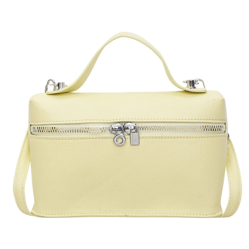 A pale yellow minimalist pebbled leather box crossbody bag with a zipper and adjustable strap.