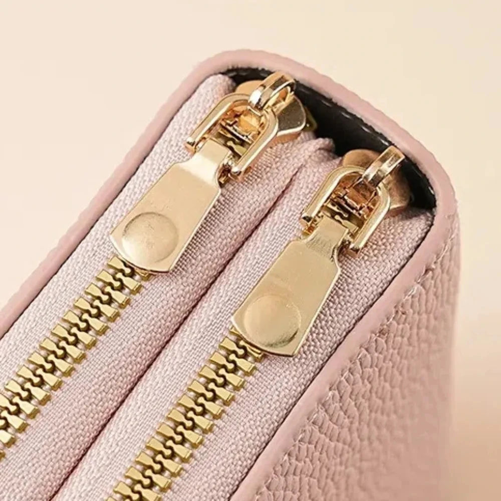 A light pink zippered wallet with gold hardware and a zipper pull visible on the front.