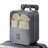 A gray portable luggage shoe organizer bag with multiple compartments resting on a silver suitcase.