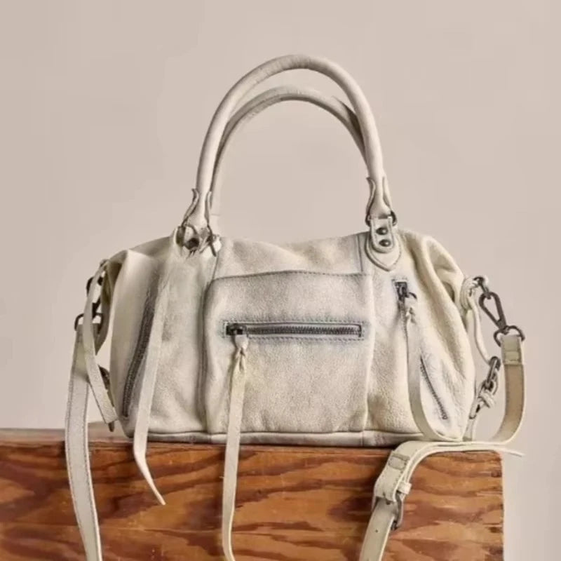 A cream-colored retro motorcycle PU leather crossbody shoulder bag resting on a wooden surface.