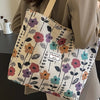 A beige bohemian corduroy tote bag with a floral pattern is held by a person.