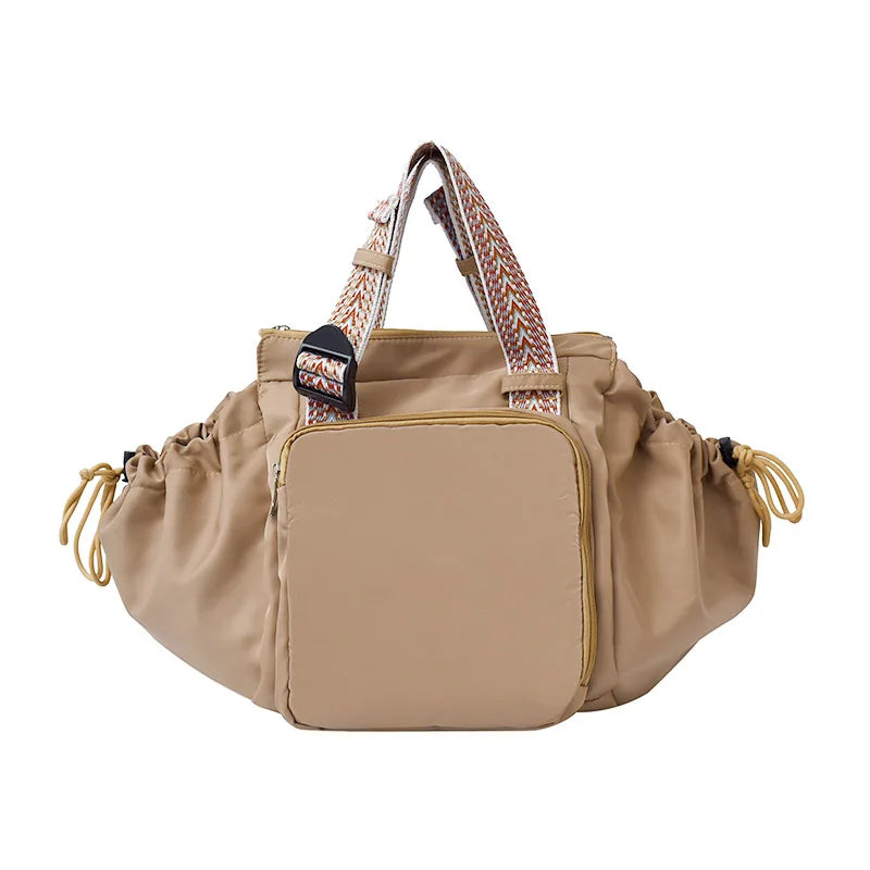 A beige nylon shoulder bag with brown patterned straps and a flap closure.