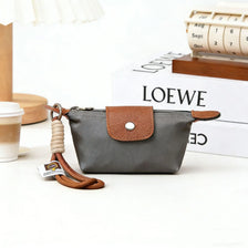 A gray compact coin purse made of nylon and faux leather with a brown leather strap and keychain.