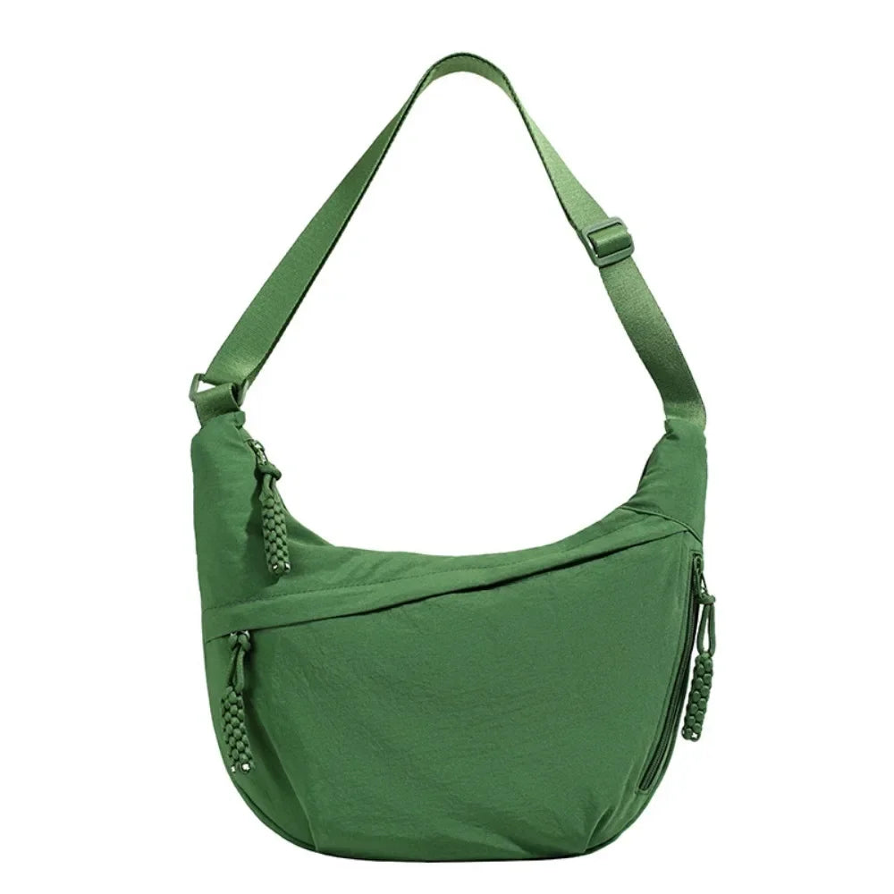 A dark green canvas crossbody bag with adjustable straps and zipper details.