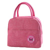 A pink insulated canvas lunch bag with a gold letter print on the lid.