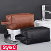 A brown leather toiletry bag and a black leather toiletry bag are shown next to a sink with a modern faucet.