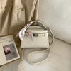 A beige elegant PU leather crossbody clutch bag with a woven strap resting on a light colored fabric.
