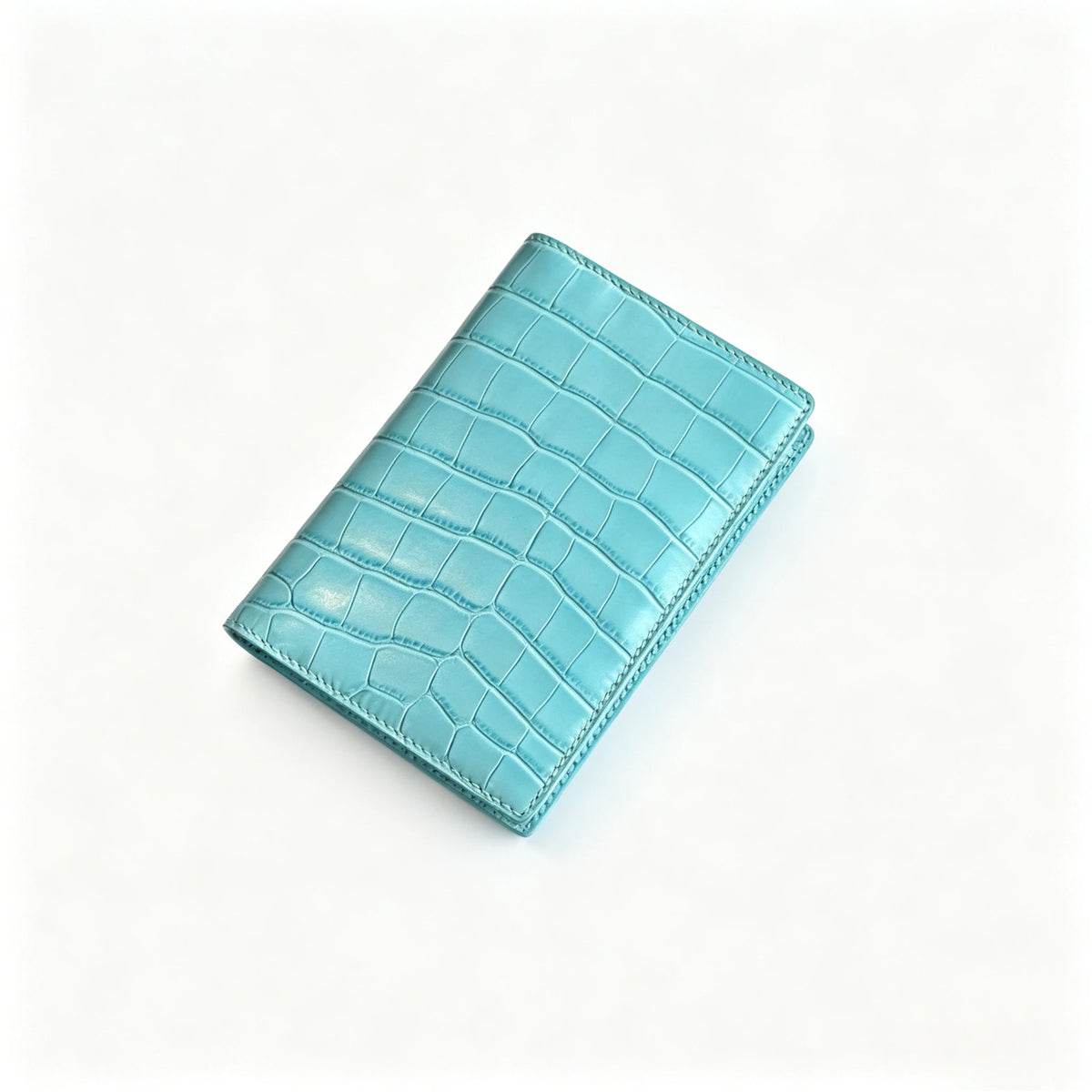 A teal genuine leather passport holder with a crocodile pattern and custom initials, shown at an angle.