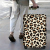 A leopard print protective luggage cover on a rolling suitcase being pulled by a person.