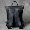 A black genuine full-grain leather backpack shown from the back.
