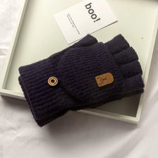 A dark purple knitted fingerless glove with a wooden button detail is displayed on a white tray.