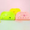 Three silicone coin pouches in yellow, lime green, and pink are displayed on a light green surface.