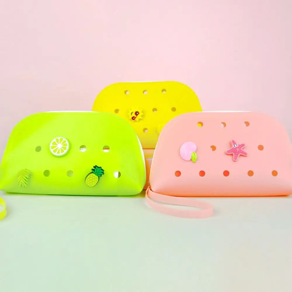 Three silicone coin pouches in yellow, lime green, and pink are displayed on a light green surface.