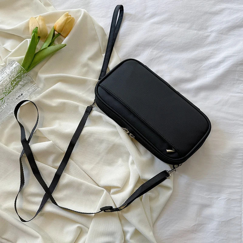 A black multi-pocket waterproof travel document organizer is displayed on a white fabric next to yellow tulips.
