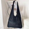 A black bohemian knit shoulder bag displayed on a shelf.