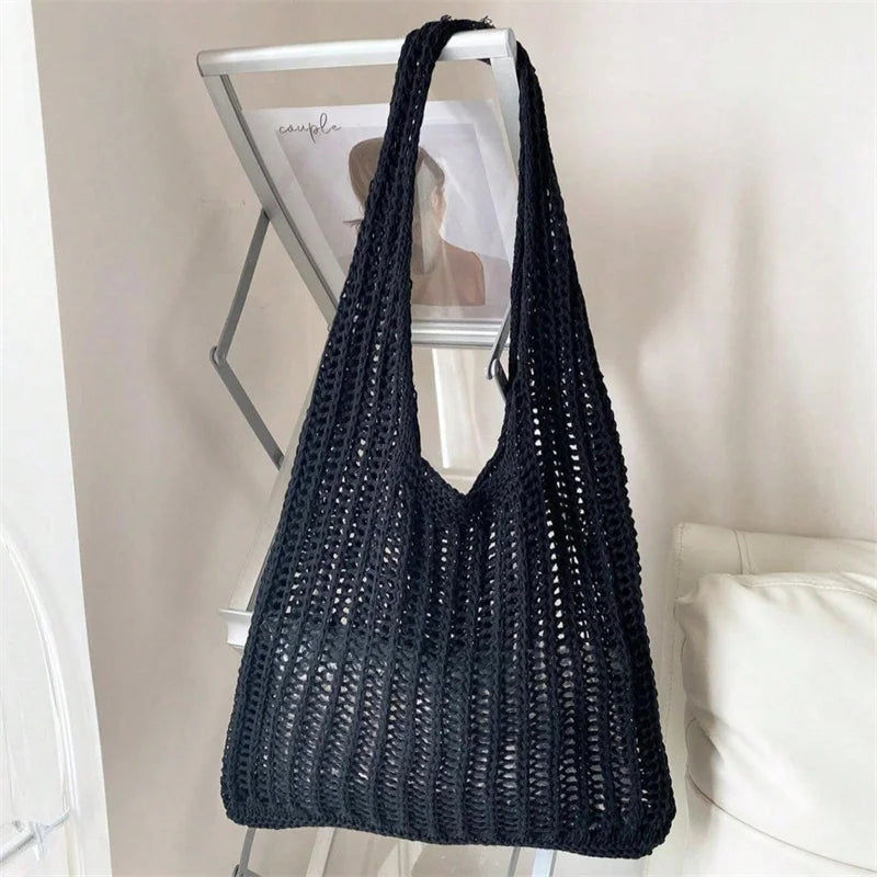 A black bohemian knit shoulder bag displayed on a shelf.