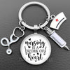 Silver keychain featuring a stethoscope charm and a circular pendant with the text Nursing is a work of heart