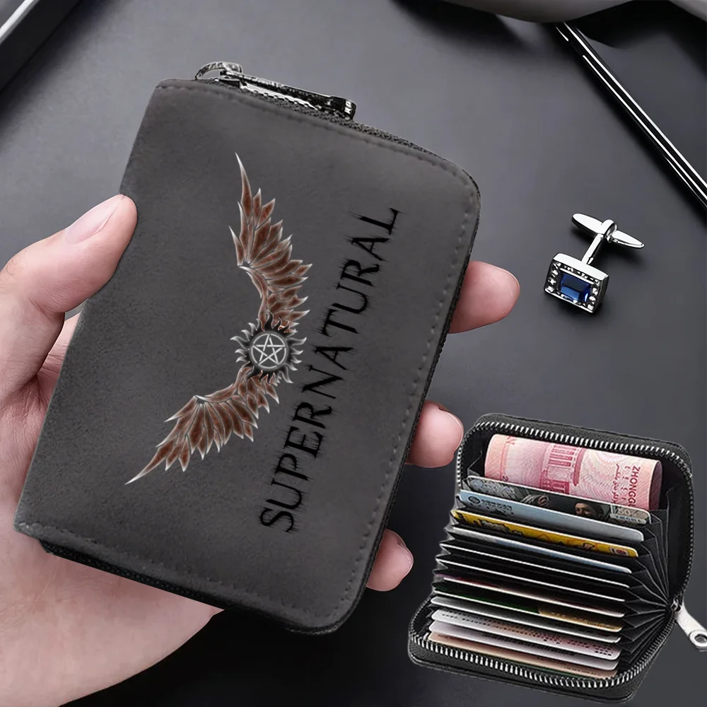 A dark gray compact card wallet with a zipper is shown being held, next to a stack of credit cards.