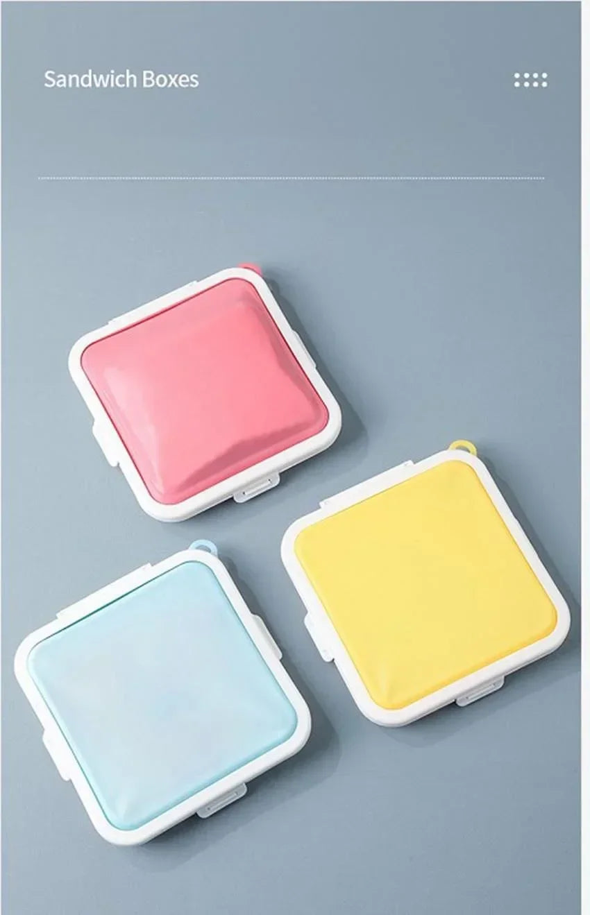 Three silicone reusable sandwich boxes in pink, yellow, and light blue displayed on a gray background.