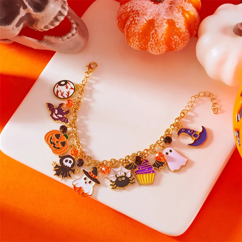 A gold charm bracelet featuring Halloween themed charms like pumpkins, ghosts, and bats displayed on a white surface.