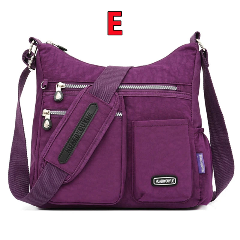 Lila wasserdichte Nylon-Crossbodybag mit schwarzem Riemen und Reißverschlussdetails.