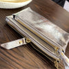 A silver metallic leather compact coin purse and key holder resting on a dark wooden surface.