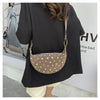 A woman holds a tan faux suede hobo crossbody bag with gold rivet accents against a white wall.