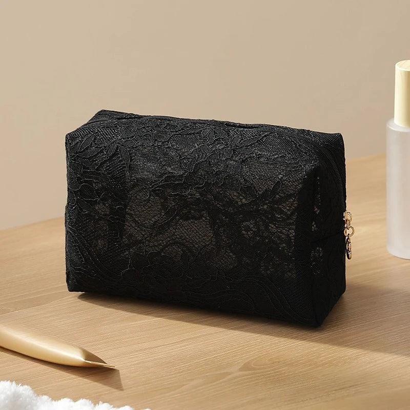 Black lace mesh cosmetic and jewelry organizer bag resting on a wooden surface.