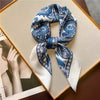 Blue and white paisley silk hair scarf tied in a bow displayed on a gold-framed card.