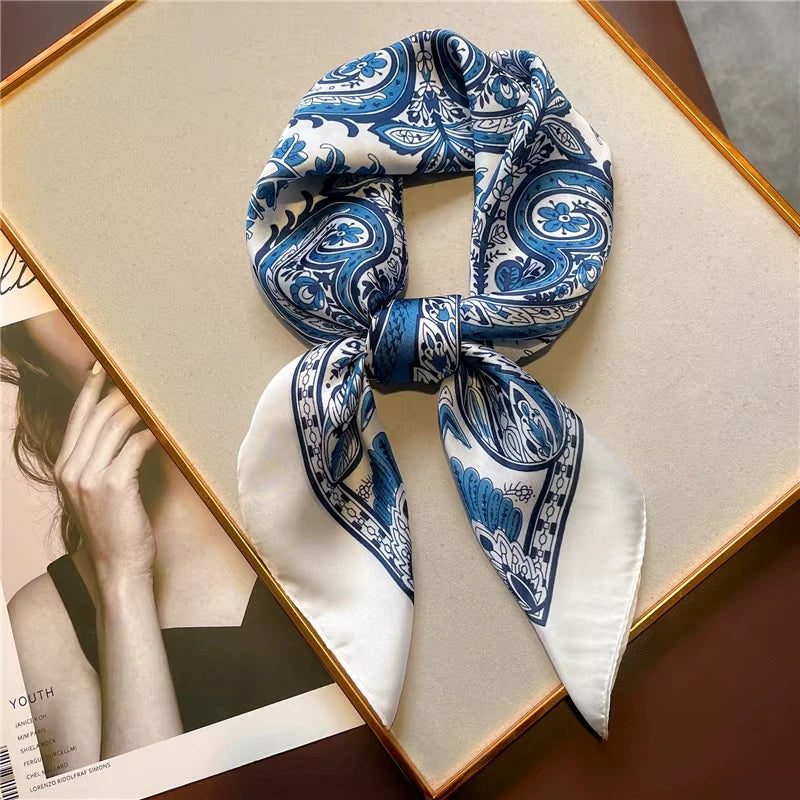 Blue and white paisley silk hair scarf tied in a bow displayed on a gold-framed card.