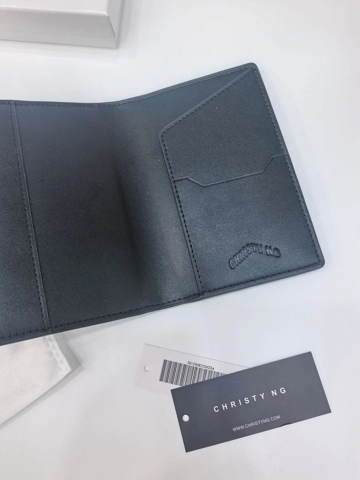 A dark gray leather passport wallet with a geometric design and stitching is shown on a white surface.