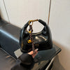 A black retro PU leather shoulder bag with a gold chain is shown resting on a dark surface.
