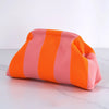 Clutch de crochet rayado tejido en tonos coral y naranja sobre una superficie blanca.
