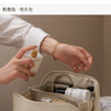 A beige foldable cosmetic storage bag is shown open, revealing various makeup products and brushes.