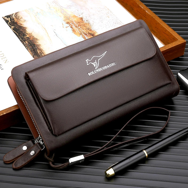 Portefeuille pochette PU marron foncé pour homme avec sangle en cuir et stylo à pointe d'or sur un plateau en bois.