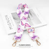 A pink and purple floral patterned nylon bag strap with gold hardware.