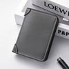 A dark gray ultra-thin PU leather credit card wallet is shown resting on a white surface next to a stack of books.