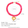 A pink resin bead necklace featuring a heart charm and stainless steel accents.